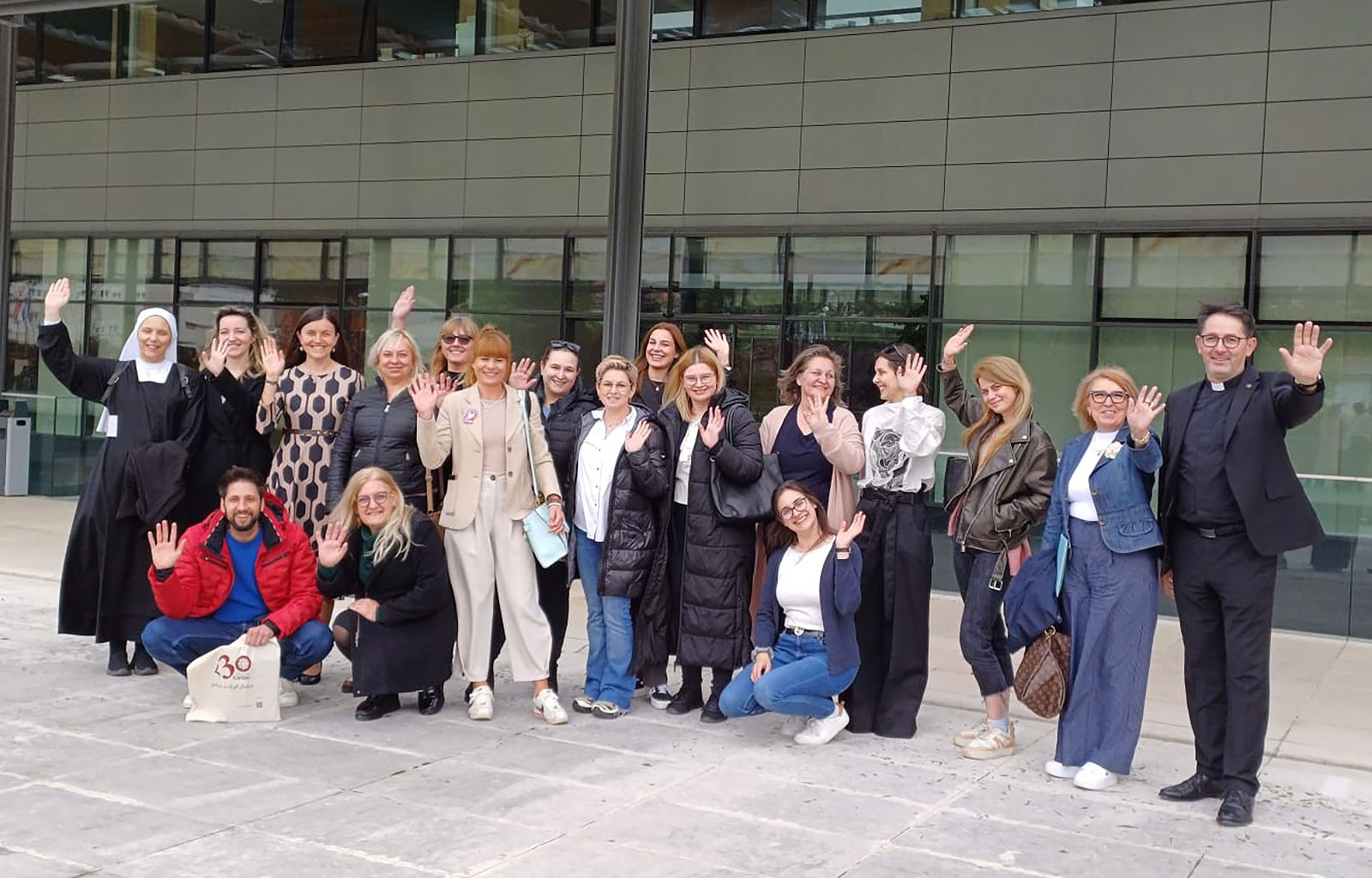 Sudionici radionice i organizatori stoje ispred zgrade Hrvatske biskupske konferencije, mašu prema kameri.